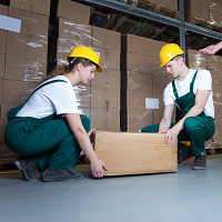 Two workers wearing safety gear lifting a box