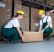 Two workers wearing safety gear lifting a box